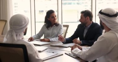 Çok kültürlü iş adamları toplantı odasında görüşmelere giriştiler. Brezilyalı ve Portekizli şirket yönetimi İslami iş ortaklarıyla müzakere ediyor, iş birliğini tartışıyor, toplantıda lider görüşmeler yapıyor.