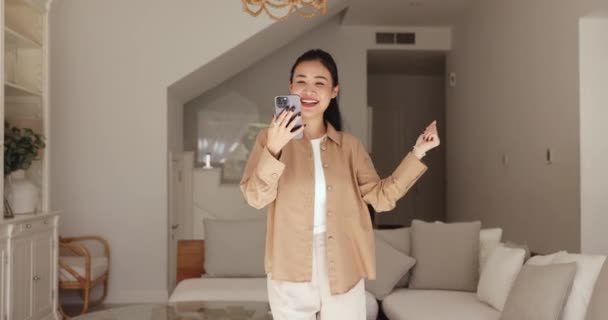 Sorunsuz Asyalı Kadın Oturma Odasında Elinde Akıllı Telefonuyla Müzik Videosu — Stok video