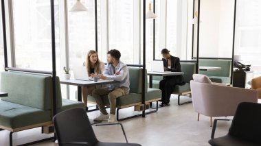 Çeşitli serbest proje yöneticileri modern iç çalışma bilgisayarlarında çalışıyorlar, masalarda oturuyorlar, dizüstü bilgisayarlarda yazıyorlar, konuşuyorlar, iş iletişimi için online teknolojiyi kullanıyorlar.