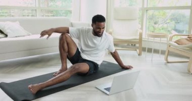 Çevrimiçi spor koçluğu kursu. Afrikalı erkek spor eğitmeni, video çağrı uygulaması ile stajyeri selamlıyor, yoga sınıfına başlıyor, evde asana dersi veriyor, modern teknoloji kullanarak insanları uzaktan eğitiyor.
