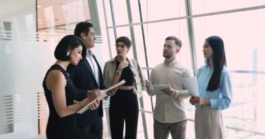 Ciddi iş arkadaşlarından oluşan çok ırklı bir ekip brifing, konuşma, çalışma görevleri, takım çalışması stratejileri ve Hintli erkek patronları dinlemek için geniş bir pencerede bekliyor.