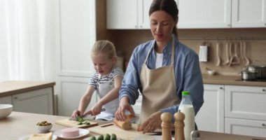 Güzel anne ve sevimli çocuk evcil önlükler giyip mutfakta sandviç hazırlıyorlar boncuk dilimliyorlar, masada sebze yiyorlar. Anne küçük kızına yemek yapmayı öğretiyor.
