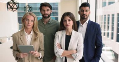 Modern ofiste kameraya poz veren dört çok ırklı iş adamı, ekip profesyonellik, birlik ve işbirliği sergiliyor. Personel portresi başarıların, satış artışlarının ve kariyerlerinin keyfini çıkarıyor