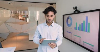 Dijital tablet araçları kullanan genç Latin işadamı, strateji ve ticareti online olarak geliştiriyor, kendine güvenen ve yetenekli görünüyor. Şirket ofisinde modern teknolojiyi, satış takip uygulamasını kullanarak çalışma
