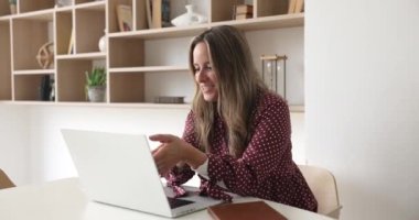 Çekici iş kadını, sanal görüşme ile meşgul olan laptop ve video uygulaması kullanarak müşteriyle konuşur, hizmet detaylarını müşteriye açıklar, uzaktan modern kablosuz teknolojiyi kullanır.