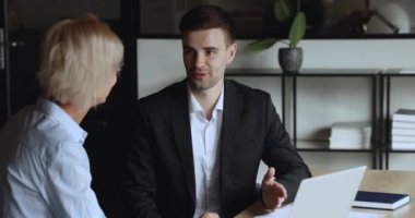 Çevrimiçi proje satan kendine güvenen genç bir yönetici. Olgun bir iş kadınına girişim. Genç ve yaşlı meslektaşlar iş yerinde dizüstü bilgisayarla konuşuyor, el sıkışıyor, gülümsüyor.