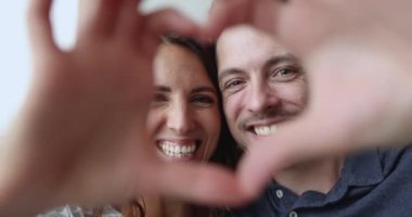 Aşırı mutlu, sevecen İspanyol çift kalp sembolü göstererek birleşik parmaklarıyla kameraya bakıyor. Romantik eşler video çeker, selfie çeker, Sevgililer Günü 'nü kutlar. Aşk, ilişkiler