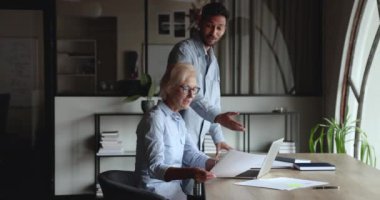 Olumlu genç Hintli iş adamı dizüstü bilgisayardaki olgun iş arkadaşına rapor veriyor. İş yerinde bilgisayarla mali belgeleri tartışan iki meslektaş