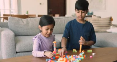 Küçük Hintli oğlan ve kız evde birlikte plastik renkli bloklar oynuyorlar. Güzel 5 'lerin kız kardeşi 8' lerin ağabeyi ile oyun oynamaktan hoşlanıyor. Gülümseme konuşması, dostça ilişkiler. Kardeşlerin oyun zamanı.