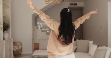 Canlı bir kadın, şık bir oturma odasında tek başına dans ediyor ya da kiralık bir evde, taşınmayı kutluyor, yeni bir günü kutluyor, mutlu görünüyor, hayatın tadını çıkarıyor, hafta sonu evde mutluluk ve enerji patlaması yaşıyor.
