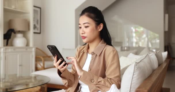 Happy Asian Fêmea Sentar Sofá Detém Verificação Smartphone Sms Expressar — Vídeo de Stock