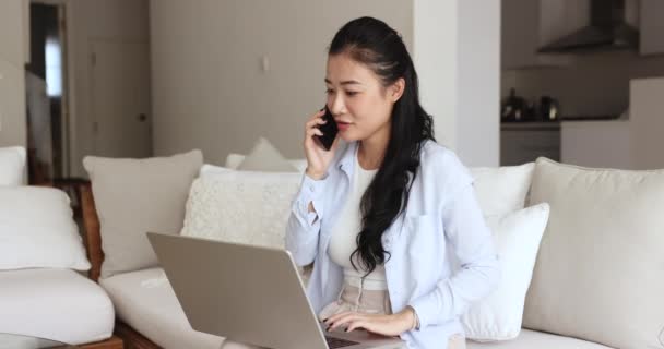 ノートパソコン付きのソファーに座る女性は スマートフォンは 顧客サービスと話し合い 商品や電子サービスを購入し 注文し 作業関連の問題 会議や締め切りを議論します テクノロジーによるコミュニケーション ストック動画