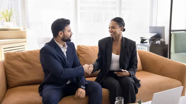 Two Happy Diverse Businesspeople Shaking Hands Working Workplace Couch Smiling Stock Image