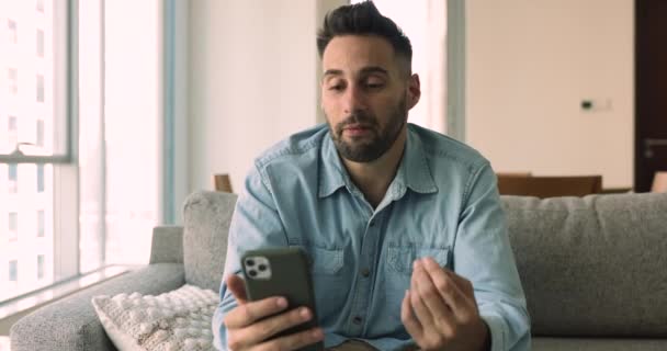 Homem Hispânico Sentar Sofá Casa Segurando Smartphone Fazer Chamada Vídeo — Vídeo de Stock