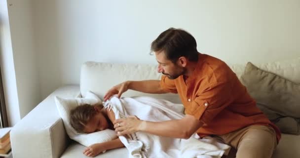 可爱的爸爸用白色温暖的格子布盖住了6岁的小女儿 可爱的孩子在客厅舒适舒适的沙发上睡着了 小女孩享受着休息 在家里睡个好觉 白天睡觉 — 图库视频影像