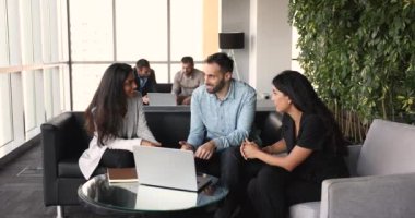 Modern ofis lobisinde dizüstü bilgisayarla aynı masada oturan üç çok ırklı iş arkadaşı. Bir grup genç takım arkadaşı iş günlerinde dostça iletişim kuruyor, işbirliği planlıyor ve projeyi tartışıyorlar.