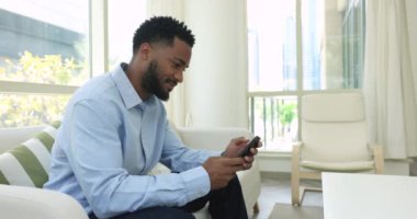 Yakışıklı Kamerun 'lu genç bekar adam akıllı telefonuyla kanepeye oturur, mobil uygulama kullanır, e-randevu hizmetlerinden zevk alır, kız arkadaşıyla uzaktan sohbet eder, mesajları ya da iş mesajlarını kontrol eder. Modern teknoloji