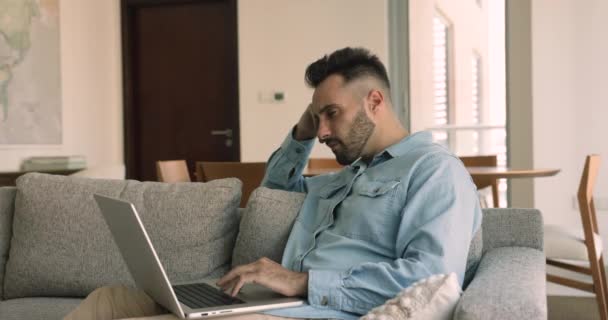 Молодий Іспаномовний Чоловік Сидить Дивані Ноутбуком Вдома Читає Електронну Пошту — стокове відео