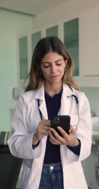 Dikey görünüm Latin dahiliyecisi, tıp çalışanı iş yerinde akıllı telefon tutuyor, klinik hastasıyla bağlantı kuruyor, tıbbi geçmişi gözden geçiriyor, laboratuvar sonuçları, ilaç listeleri reçeteli yönetim uygulaması kullanıyor
