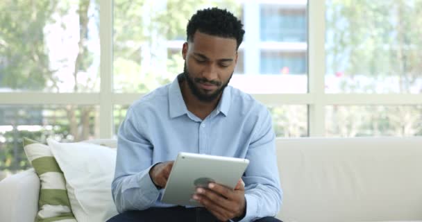 Afrikai Férfi Ülni Pihenés Kanapén Nézd Meg Digitális Tabletta Képernyő — Stock videók