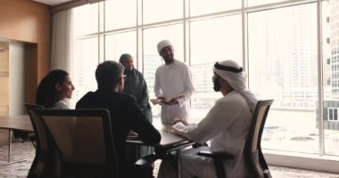 Beş iş adamı, çok uluslu takım, geleneksel giysiler içinde Müslüman iş arkadaşları ve müşteriler konferans salonunda görüşmeler yapıyor, brifinge katılıyor, çalışma sonuçlarını gözden geçiriyor, plan yapıyor, iş stratejisini paylaşıyorlar.