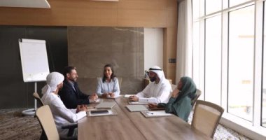 Beş çok uluslu ofis çalışanı modern konferans odasında brifinge katılıyor, başlıca sohbet, fikir ve çözümleri paylaşıyor. Müslüman işadamları toplantı odasında müzakere sürecine giriştiler