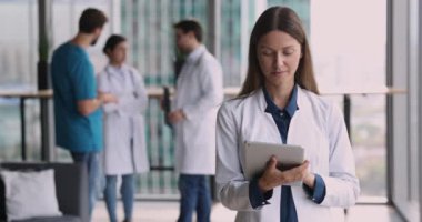 Çekici genç kadın pratisyen doktor dijital tablet kullanıyor, uzaktan e-posta yazıyor, sörf bilgisi alıyor, ajanda ya da programa bakıyor, toplantıyı yönetiyor. Sağlık hizmetleri, tıbbi uygulamalar