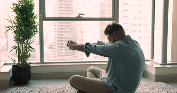 Hombre Joven Estira Los Músculos Sentados Suelo Apartamento Rascacielos Moderno — Vídeo de stock