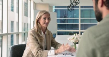 İş kadını masasında oturup şirket müşterisi, ortağı ya da yatırımcısı ile resmi müzakere görüşmesi yapar, anlaşmaya varır, işbirliği ve gelecekteki ortaklığa el sıkışarak saygı gösterir.