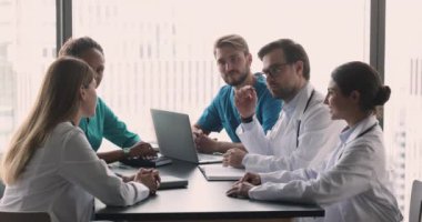 Beş genç 35 'lik çok ırklı doktor klinikte grup brifingine katılıyor, hasta hastalıkları tedavisi hakkında görüşlerini paylaşıyor, ekip çalışması yapıyor hastane konferans odasındaki masada oturuyor.