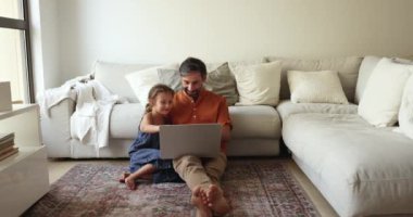 Sevgi dolu baba ve kız oturma odasında oturup dizüstü bilgisayar kullanıyor, internetten alıyor, çizgi film ya da film seçiyor, yeni başvuru formları öğreniyor evde vakit geçiriyor. Eğlence veya eğitim için modern kablosuz teknoloji kullanımı