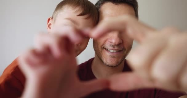 愛する成熟した父親と小さな6人の息子は カメラへの愛のシンボルを示し 接合された指を通して顔のビューを閉じるハートサインを作ります 家族の絆 サポート ハッピーファザーズデーのお祝い — ストック動画