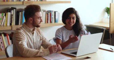 Modern ofiste iki farklı meslektaş sohbet ediyor, proje üzerinde birlikte çalışıyorlar, dizüstü bilgisayar kullanıyorlar, ortak plan hazırlıyorlar, pozitif iş kadını genç erkek partnerle fikir paylaşıyor, müşteriye danışıyorlar.