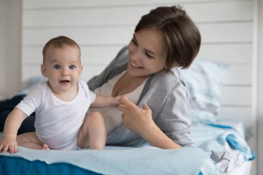 Genç, sevecen, beyaz bir anne rahat bir yatakta uzanıyor, güzel, yeni doğmuş bir bebeğin minicik kollarını tutuyor, sabah yatak odasında mutlu bir aile portresi çiziyor. Annelik, bebeklik, yeni nesil