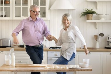 Neşeli yaşlı koca ve olgun eş ev mutfağında müzik eşliğinde dans ediyor, süslü masalarda eğleniyor, ev yapımı hamur işi pişiriyor, tatlı pişiriyor, aktif yaşam tarzını sürdürüyor.