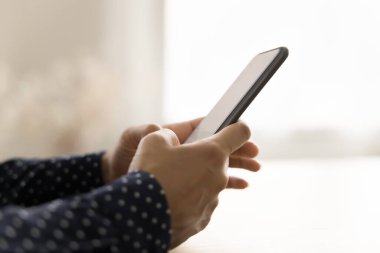 Masadaki kadınların elindeki siyah akıllı telefonun yan görüntüsü. Cep telefonuyla yazan genç bir iş kadını, iş için internet uygulamasını, iletişim için dijital cihazda online servisi kullanıyor. Yakın çekim.