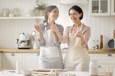 Neşeli 35 'li yaşlardaki genç bir kadın ve önlüklü 60' lı yaşlardaki annesi ellerini çırpıp eğlenirken beyaz un serpiştiriyorlar ve evde yemek hazırlıklarının keyfini çıkarıyorlar. Hafta sonu aşçılığı, aile tarifi