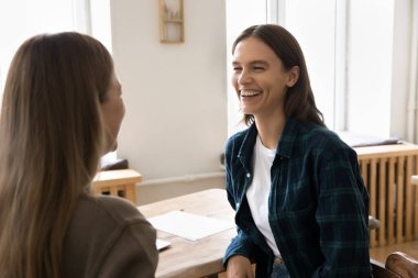 Neşeli genç profesyonel kadın günlük kıyafet toplantısında ve bayan meslektaşımla konuşurken, sohbet ederken, gülerken, eğlenirken, iş kurma projesini tartışırken.