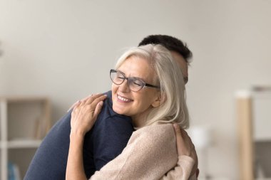 Şefkatli bir son sınıf annesi oğluyla evde tanışır, kucaklaşır, gözleri kapalı yetişkin bir çocuğu kucaklar, sevgi, şefkat, minnettarlık hisseder. Olgun anne portresi.