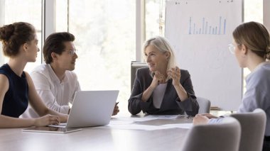 Kendinden emin orta yaşlı bir iş kadını yönetim kurulunda ekiple buluşuyor çalışanlarla konuşuyor, gülüyor, gülümsüyor. Şirket danışmanı, stajyerlere ders veriyor.