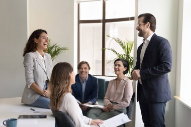 Kendine güvenen iş adamı ekibe sesleniyor, çalışanları motive ediyor, komik hikayeler anlatıyor. Neşeli iş arkadaşları kısa bir toplantıda sohbet ediyorlar, iş arasında proje tartışıyorlar, gülüyorlar..