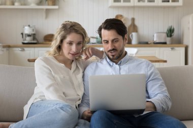 Yakışıklı koca evde dizüstü bilgisayar kullanıyor, eşiyle konuşuyor, ekranı gösteriyor. Milenyum çifti internetten alışveriş yapıyor, internetten otel rezervasyonu yaptırıyor, evdeki kanepede oturuyor, bilgisayar tutuyor.