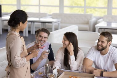Kafedeki mutlu müşterileri dinleyen, notlar yazan, masada duran Hintli garson. Arkadaşlardan oluşan bir grup restoranda sipariş veriyor, masada yemek ve içeceklerle oturuyor.