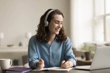 Kablosuz kulaklıklı mutlu öğrenci kız online eğitimin tadını çıkarıyor, bilgi alıyor, webinar izliyor, ders veriyor, öğrenme konferansı yapıyor, gülümsüyor, gülüyor, konuşuyor.
