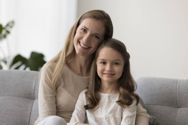 Neşeli, mutlu bir anne ve sevimli, güzel bir kız çocuk portresi. Anne çocuğuna sevgiyle, özenle, şefkatle sarılıyor, kameraya bakıyor, gülümsüyor, anneliğin tadını çıkarıyor, aile bağlarını kuruyor.
