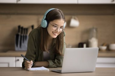 Neşeli zeki online öğrenci kız video, webinar, deneme, makale, araştırma çalışması için özet yazma, evde eğitim için internet iletişimini kullanma