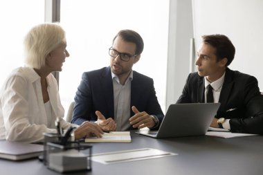 İşletme proje lideri çalışanlarla pazarlama stratejisini tartışıyor, görev planlama, takım çalışması, iş arkadaşlarıyla, ortaklarla konuşuyor, dizüstü bilgisayarla toplantı masasında oturuyor.