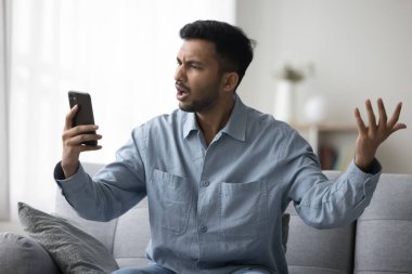 Öfkeli genç Hintli adam internet iletişimi, uygulama, yazılım işi, servis arızası, akıllı telefon ekranına bakma, cep telefonu tutma, kızma, sinirlenme...