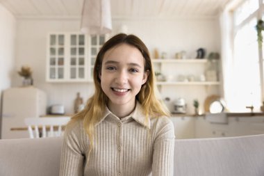 Neşeli, güzel, liseli genç kız görüntülü konuşma yapıyor, internette sohbet ediyor, sohbetin tadını çıkarıyor, internet iletişimi kuruyor, dişlek gülümsemeyle kameraya bakıyor. Ev portresi