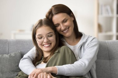 Sevecen, şefkatli, gülümseyen ve gülen güzel bir anne, gözlüklü güzel bir okul çocuğuna sarılıyor. Anne ve genç çocuk yakın ilişkinin tadını çıkarıyorlar, kaynaşıyorlar.